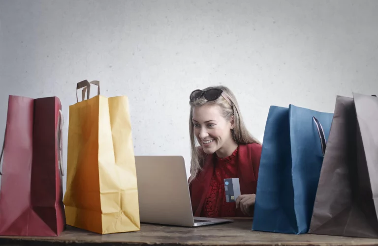 Smiling woman shopping online with bags.