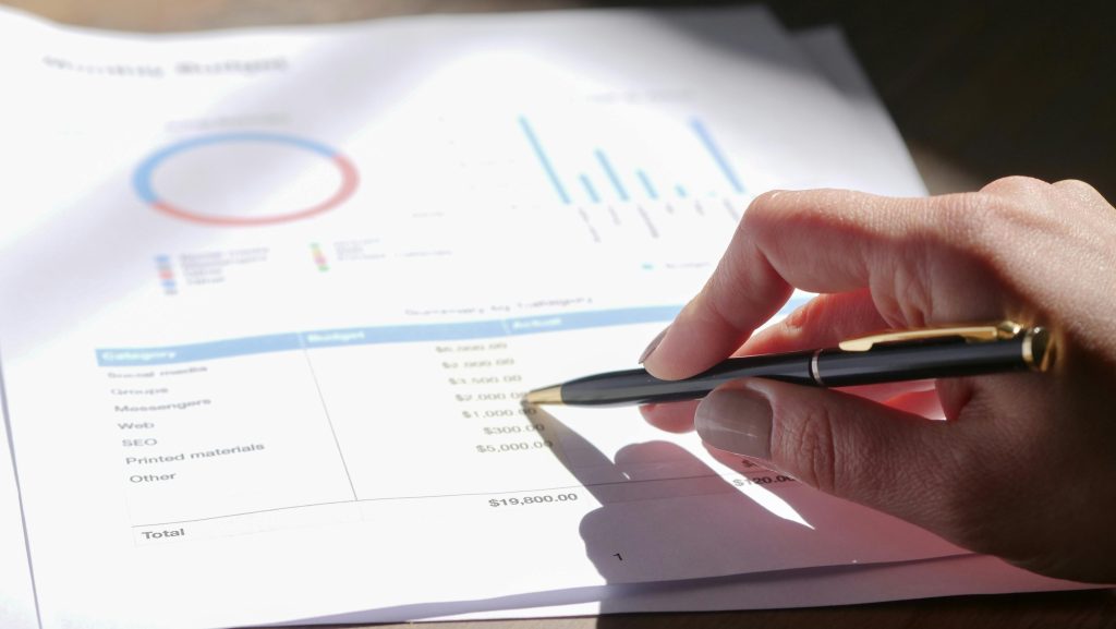 Main analysant des graphiques financiers avec un stylo