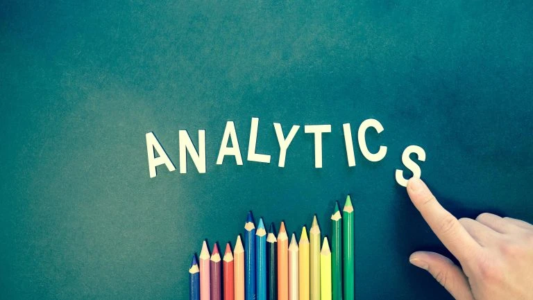 Word 'ANALYTICS' with coloured pencils and pointing finger