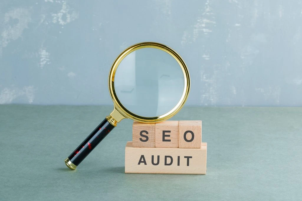 Magnifying glass and SEO AUDIT blocks on blue background