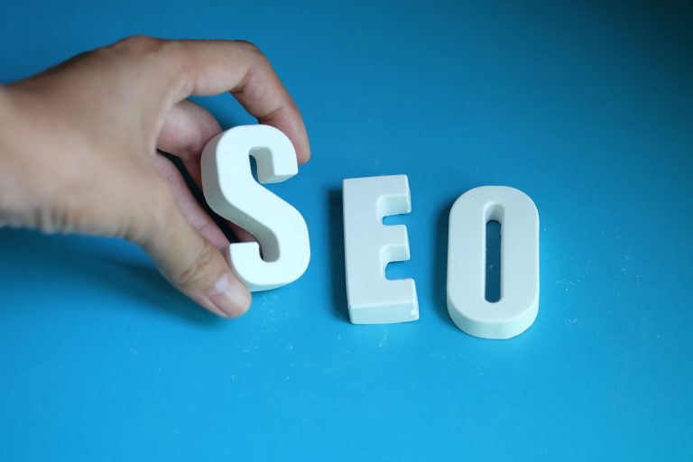 Hand placing SEO letters on a blue background