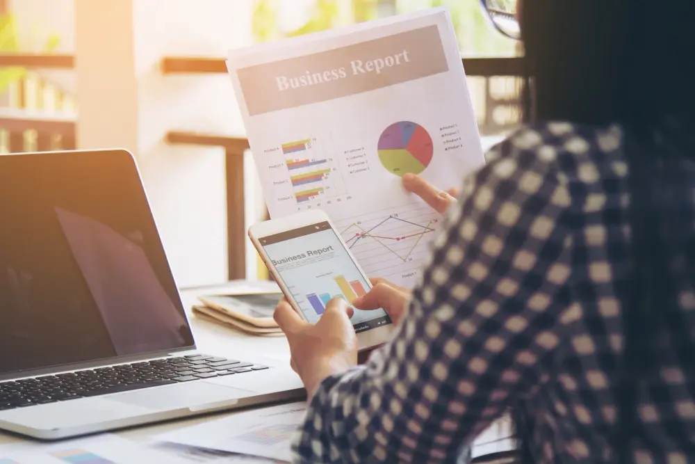 Woman analyzing paper and mobile reports