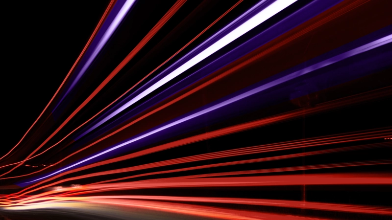 Traînées lumineuses rouges et violettes sur fond noir